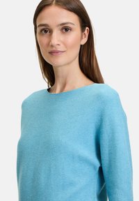 Helles blaues Sweatshirt mit Rundhalsausschnitt, strukturiertem Strickstoff und lässiger Passform. Lange Ärmel und ein feines Rippmuster über das gesamte Kleidungsstück.