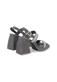 Sandalias de tacón alto de denim negro con tacones cuadrados gruesos, con tirantes de acento plateado y cierre de hebilla ajustable.