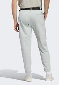 Light mint green athletic pants with an elastic waistband, tapered legs, and two back pockets. Features an Adidas logo on the back.