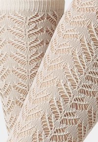 Beige Spitzenstrumpfhose mit Blattmuster, feiner Stricktextur und elastischem Bündchen für einen engen Sitz. Vertikale Linien sorgen für einen transparenten Look.