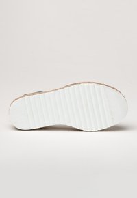 Suela de zapato blanca con textura estriada, con un borde de color marrón claro. La suela parece plana y está hecha de caucho o material similar.