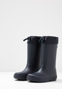 Bottes de pluie en caoutchouc navy avec un haut en textile matelassé, cordon de serrage ajustable, semelles texturées et bouts ronds pour une meilleure adhérence.