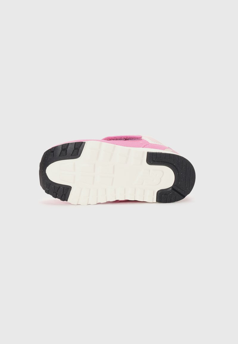 Zapatilla rosa con un upper texturizado, que presenta una entresuela blanca y una suela de goma negra, exhibiendo un patrón de ondulación para el agarre.