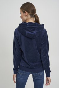 Tmavomodrá velúrová mikina s pohodlnou kapucňou, rebrovanými manžetami a lemom. Tkanina má jemnú textúru bez výrazných vzorov.