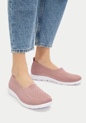 Zapatos sin cordones de color rosa hechos de tela tejida con un patrón texturizado, complementados con una suela de goma blanca y ribete elástico. Diseño casual pensado para la comodidad.
