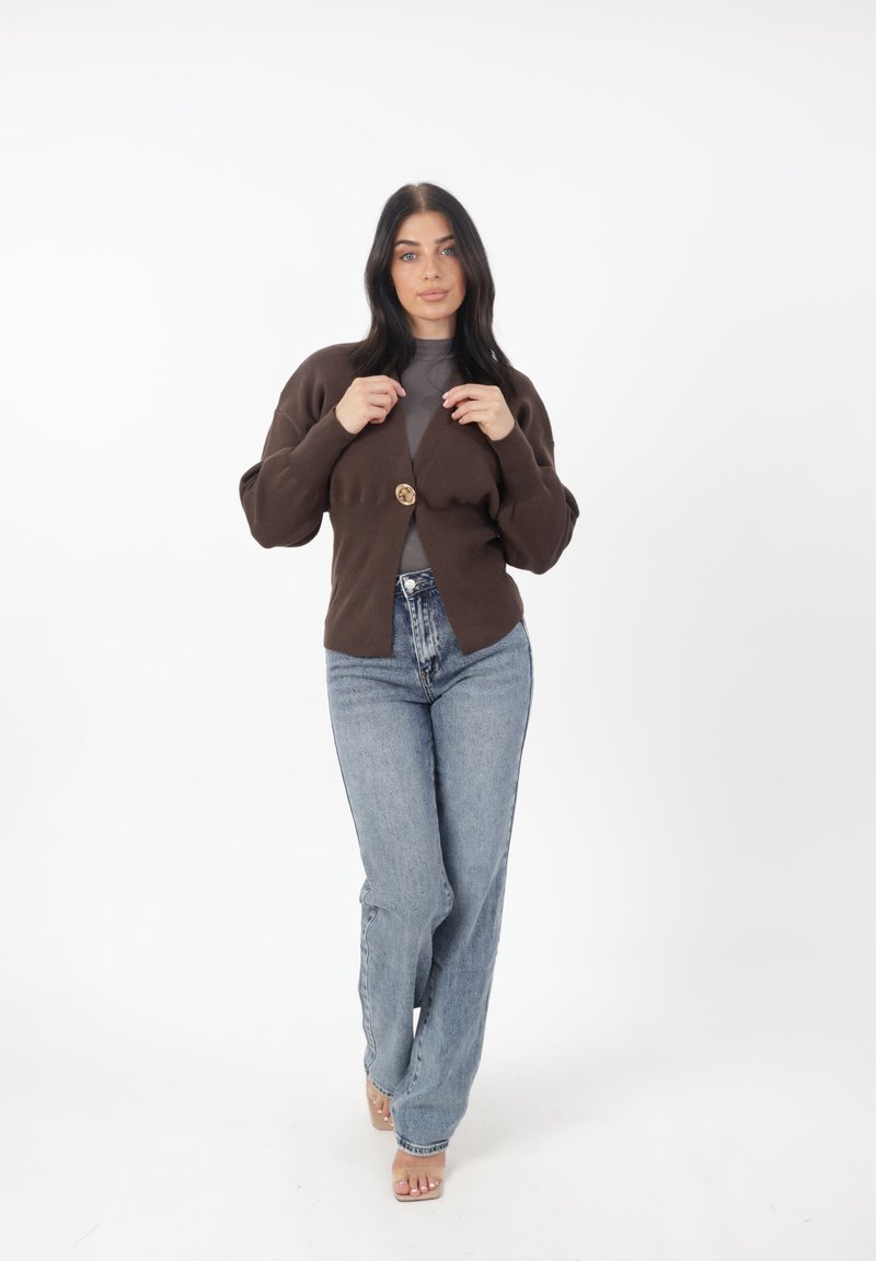 Brun stickad cardigan med knappstängning framtill, ballongsärmar, tillsammans med hög midja ljusblå jeans. Enfärgad, mjuk textur.