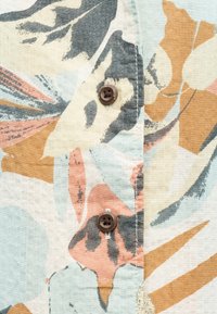 Ελαφρύ ύφασμα με αφηρημένο ανθικό μοτίβο σε υποτονικό πορτοκαλί, γκρι, μπλε και μπεζ, με δύο καφέ κουμπιά ραμμένα κατακόρυφα.