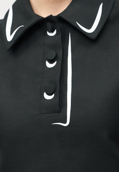 Μαύρος γιακάς πουκάμισου με τρία μαύρα κουμπιά, καθένα με λευκά σχέδια σε σχήμα λοξοτομίας, και άσπρες τρέσες κατά μήκος της λωρίδας κουμπιών και των άκρων του γιακά.