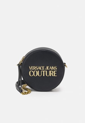 Ronde zwarte leren crossbodytas met gouden kettingriem en gouden opschrift "Versace Jeans Couture" aan de voorkant.