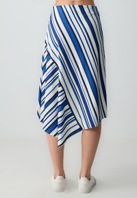 Jupe rayée bleue et blanche avec un ourlet asymétrique, faite de tissu à côtes ; présente des rayures verticales et horizontales de largeurs variées.
