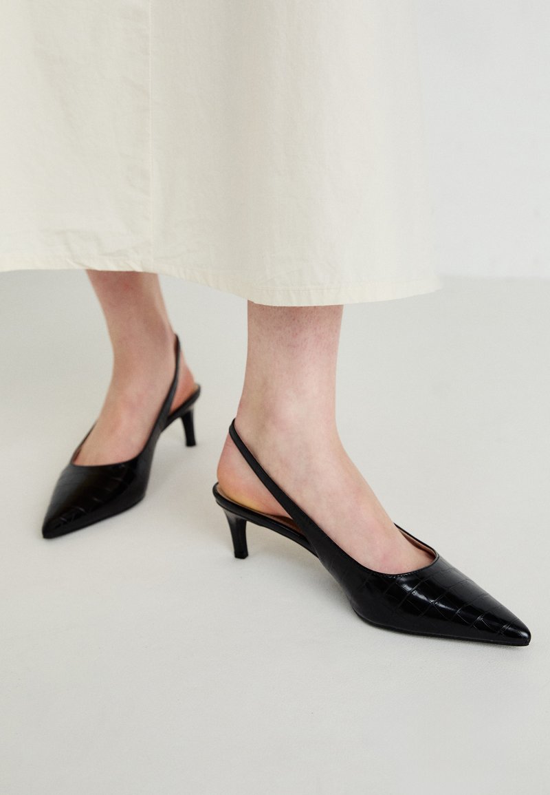 Pantofi cu toc slingback cu vârf ascuțit, de culoare neagră, cu un model texturat de crocodil, toc subțire și design deschis la spate. Materialul pare lucios și elegant.