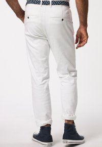Pantaloni in cotone bianchi con vestibilità slim, con orli arrotolati e due tasche posteriori. Abbinati a sneaker alte blu.