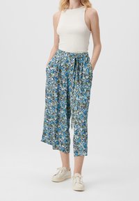 Blommönstrade, lätta, blå vida byxor med elastisk midja, dragsko-detalj och sidofickor, ihopparat med en ribbad vit ärmlös topp.