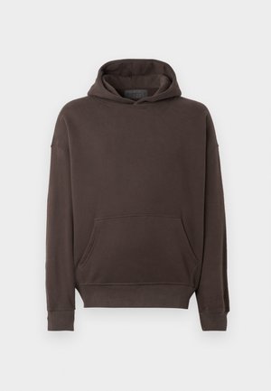 Hnědá mikina s kapucí vyrobená z měkké tkaniny, která má přední kapsu, žebrované manžety a volný střih. Jednoduchý design bez vzorů.