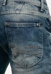 Jeans in denim con un lavaggio azzurro chiaro, caratterizzati da una tasca posteriore con dettagli di cucitura e logo del marchio in rilievo "CIPO&BAIXX".