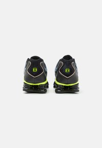 Sapatos desportivos pretos com um upper texturizado, detalhes verdes e um design de sola transparente. Apresenta um calcanhar almofadado e costuras reforçadas.