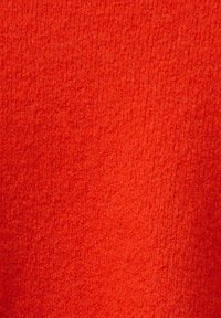 Roter, strukturierten Stoff mit einem weichen, flauschigen Aussehen. Das Material zeigt ein dichtes Strickmuster, das einen warmen und gemütlichen Look vermittelt.