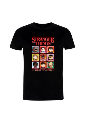 Camiseta negra con arte pixelado de nueve personajes de "Stranger Things" y texto en rojo "SELECT PLAYER" encima de la cuadrícula.