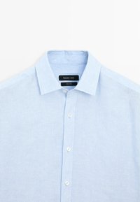 Camicia di lino blu chiaro con un delicato motivo a righe, dotata di colletto classico e chiusura con bottoni. Etichetta: Massimo Dutti.