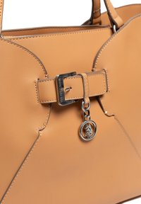 Torebka z brązowej skóry o strukturalnym kształcie, z zapięciem na klamrę i srebrnymi elementami, w tym detalu z zawieszką. Gładka faktura.