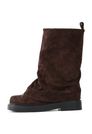 Stivale in suede marrone a metà polpaccio con gambale morbido, punta rotonda, suola in gomma nera e tab a strappo sul retro.