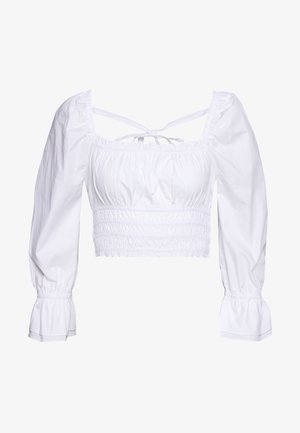 Biała bluzka w stylu crop top uszyta z bawełny, z marszczonym krojem, bufkowymi długimi rękawami oraz regulowanymi tasiemkami z tyłu. Prosty i teksturowany design.