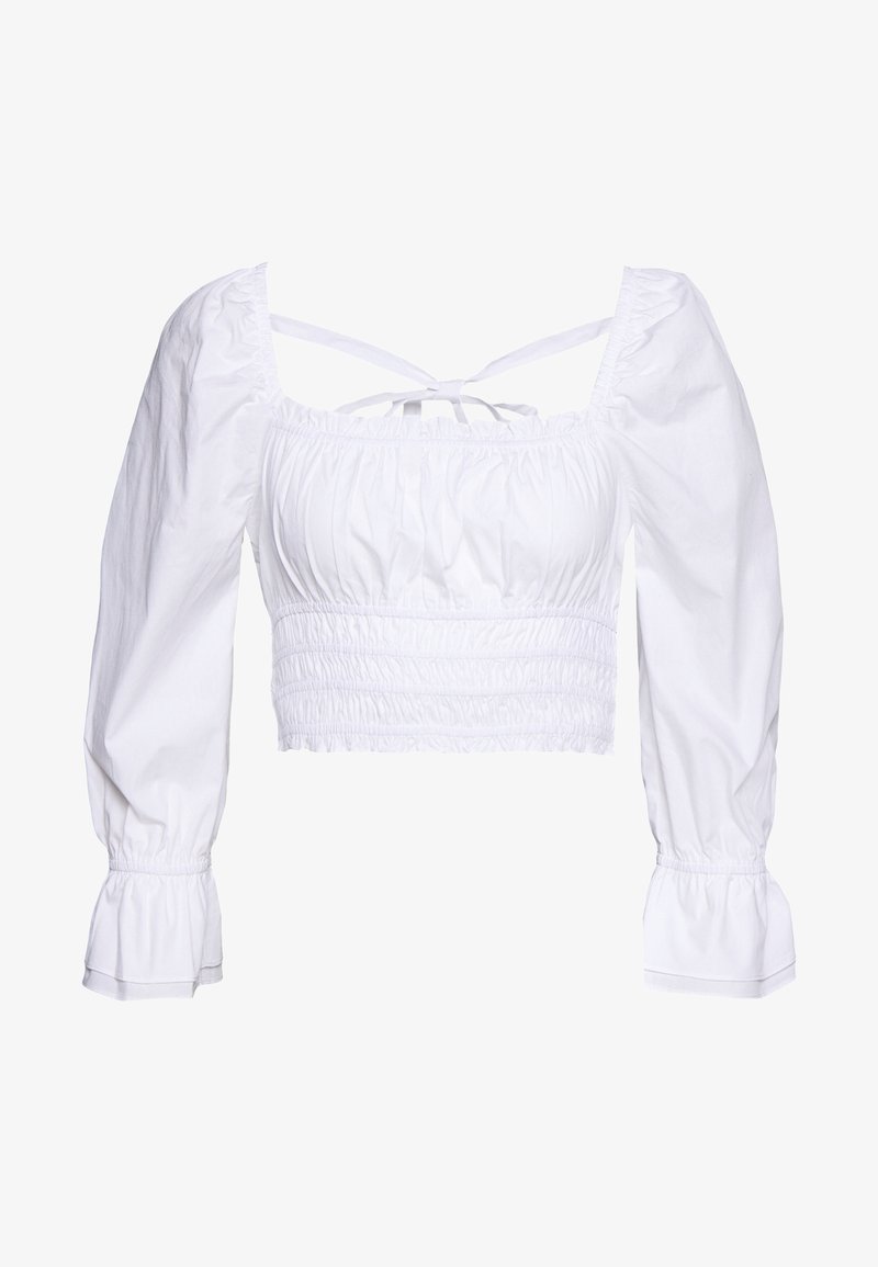 Top court blanc en coton avec un corsage smocké, des manches longues bouffantes et des liens réglables à l’arrière. Conception simple et texturée.