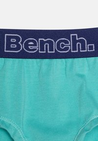 Bokserki z tkaniny w kolorze aqua zielonym z granatowym elastycznym pasem, na którym w białym napisie widnieje słowo "Bench." Gładka tekstura i standardowy krój.