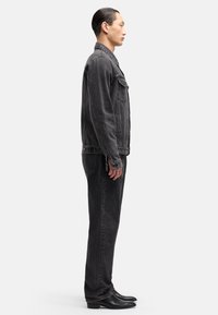 Schwarze Denimjacke und Hose mit taillierter Silhouette. Verfügt über kontrastierende Nähte, Seitentaschen und glänzende schwarze Stiefeletten.