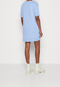 Ljusblå oversized sweatshirtklänning med korta ärmar, med en rak skärning och sidoflikar, tillsammans med tjocka krämfärgade ankelstövlar.