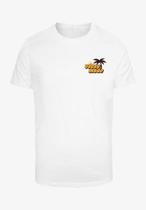 T-shirt bianco a maniche corte con la scritta "vacay mode" in giallo e marrone, accompagnata da una piccola grafica di una palma.