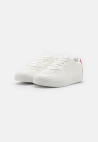 Hvite lær sneakers har perforert tå, rosa detaljer på hælen, flate snøringer og en teksturert gummisåle.