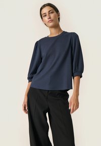 Navyblauw, korte mouwen top met een ronde halslijn, voorzien van pofmouwen en een iets uitlopende zoom; gladde stofstructuur.