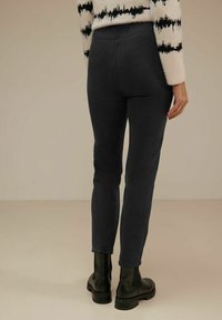 Dark grey, stretchy leggings with a fitted design, high waistband, and smooth texture, paired with black ankle boots.