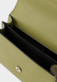 Billetera de cuero verde claro abierta con interior de tela negra y cierre magnético plateado sobre un fondo blanco.