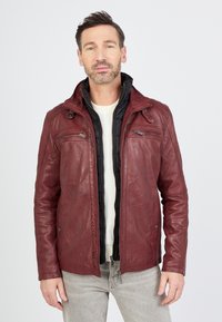 Rote Lederjacke mit Reißverschlusstaschen, geschichtet über einem schwarzen, isolierten Futter. Mit Stehkragen und glatter Textur.