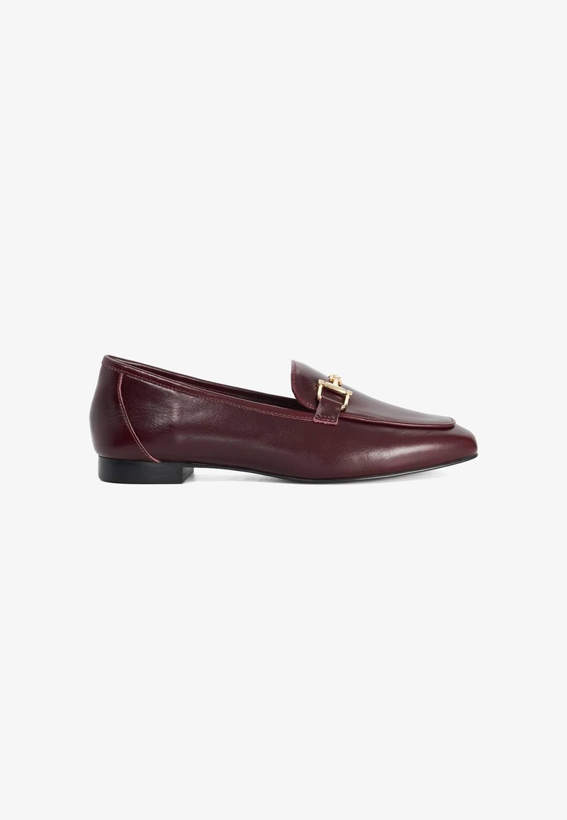 Mocassin plat en cuir bordeaux avec détail boucle dorée et petit talon noir, présenté en vue latérale sur fond blanc.