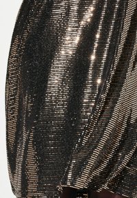 Schwarzer und goldener Paillettestoff mit einer schimmernden Textur, der einen diagonalen Fall und unterschiedlich große runde Pailletten aufweist.