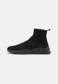 Chaussures de style basket noires avec un upper en tricot texturé, un col haut et une semelle en caoutchouc épaisse. Design simple avec une construction sans couture.