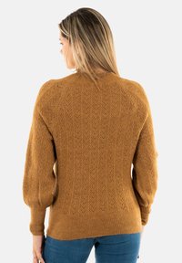 Suéter de punto color mostaza con un patrón en espiga texturizado, puños y dobladillo acanalados, que presenta mangas tipo globo y cuello redondo.