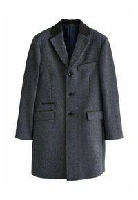 Sötétszürke, gyapjúkeverék overál texturált mintázattal, kivágott gallérral, három gombbal és két oldalsó zsebbel. Fekete szövetből készült kiegészítők.