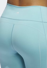 Leggings azzurro chiaro a vita alta realizzati in tessuto elasticizzato, con cuciture piatte e un logo ricamato vicino all'elastico in vita.