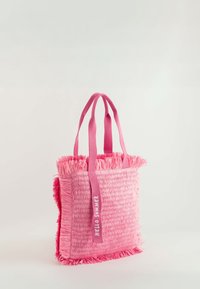 Rosa axelväska med en texturerad design som liknar halm, fransade kanter och rosa tyghandtag. "HELLO SUMMER" är tryckt på en rem.