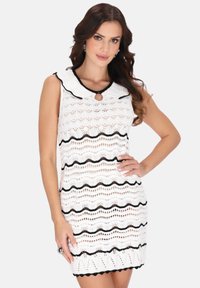 Rochie albă tricotată cu accente negre în formă de val, având un guler rotund și un detaliu în formă de cheiță, design fără mâneci și model cu țesătură deschisă.
