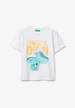 Biały dziecięcy t-shirt z napisem „Pod oceanem”, niebieską falą, małą czerwoną rybką i przymocowaną turkusową kieszonką z rysunkiem rekina.