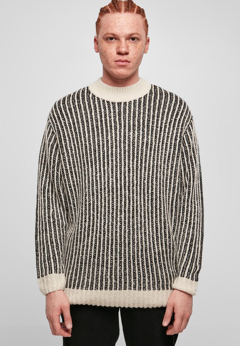 Maglione lavorato a maglia con strisce verticali bianche e nere, colletto rotondo e polsini a costine. Texture morbida e design dalla vestibilità ampia.