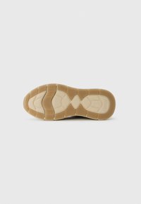 Suola di scarpa in gomma color marrone chiaro e beige con un motivo di battistrada segmentato e nome del marchio impresso vicino al tallone.