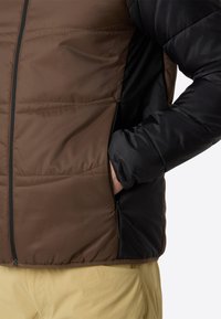 Puffjacke mit einem Farbblockdesign in Braun und Schwarz, ausgestattet mit einem Reißverschluss, strukturierter Stoff und seitlichen Taschen.
