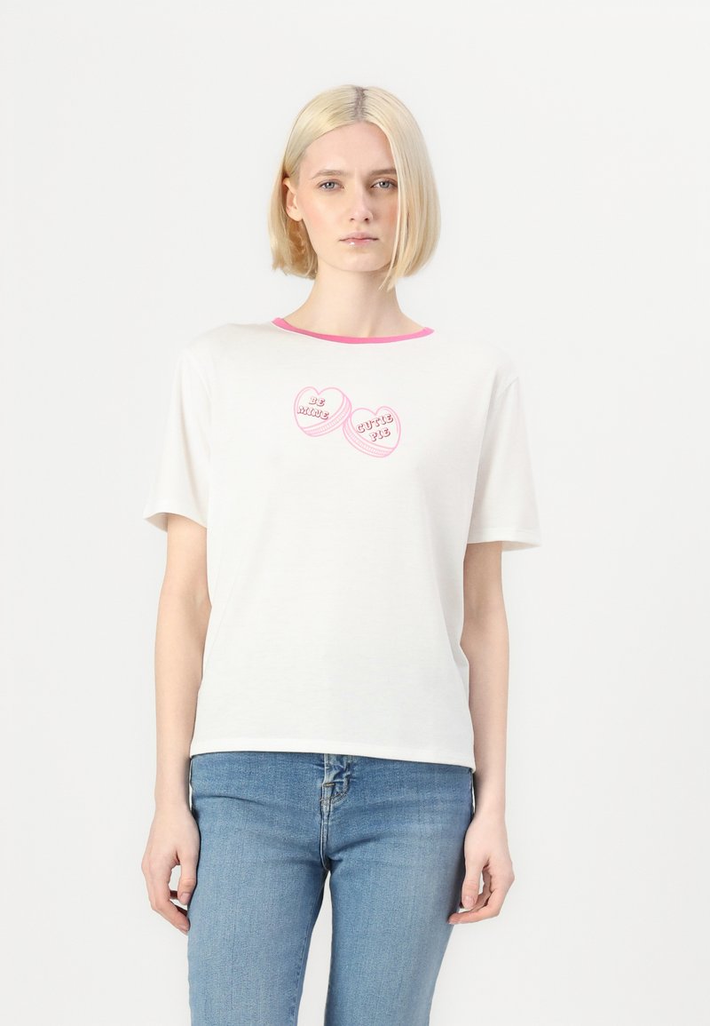 T-shirt branco de manga curta com decote rosa, apresentando designs em forma de coração que dizem "Seja Meu" e "Doçura" em texto rosa.