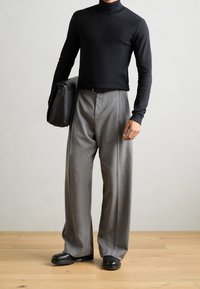 Grau weite Hose, schwarzer Rollkragenpullover, schwarze Ledertasche. Glatte Textur, minimalistisches Design, vor neutralem Hintergrund. Schwarze Schuhe mit markanten Sohlen.